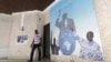 A man walks near a poster showing portraits of former Ivory coast president Laurent Gbagbo (C) and Former Ivory Coast prime minister Pascal Affi N'Guessan (R), leader of Ivorian Popular Front (FPI) at the FPI headquarters in Abidjan, September 2, 2015.