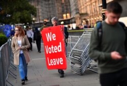 A pro-Brexit protester carries signs outside the Houses of Parliament in London, Sept. 4, 2019.