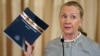 Secretary of State Hilary Rodham Clinton holds up a copy of the 2012 Trafficking in Persons Report at the State Department in Washington, June 19, 2012.