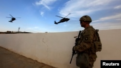 资料照片：美军在伊拉克摩苏尔袭击伊斯兰国武装分子的行动中，一名美国陆军士兵手持武器站在摩苏尔附近地区的军事基地。2016年10月18日拍摄。 （路透社照片）