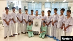 泰国野猪少年足球队员和教练手持在救援过程中丧生的前海军海豹突击队员的画像在清莱的医院合影。（2018年7月14日）