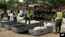 Polisi Kolombia membawa tas-tas berisi korban tewas dalam bus yang terbakar di kota Fundacion, Minggu (18/5).