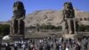 Tourists look at the Colossi of Memnon, two massive stone statues of Pharaoh Amenhotep III, on the west bank of the Nile River at Luxor, 510 kilometers (320 miles) south of Cairo, Egypt, Dec. 1, 2014. 