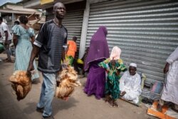 FILE - A man carries chickens for sale in a market in Accra, Ghana, on May 13, 2021 during Eid Al-Fitr prayer that marks the end of the Holy month of Ramadan.