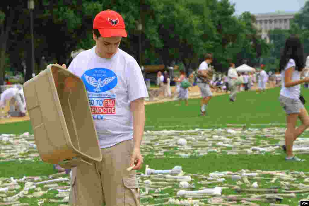 Tenaga sukarela menaruh tulang-tulang simbolis pada instalasi &quot;One Million Bones&quot; (Sejuta Tulang) di taman National Mall, Washington DC (8/6). (VOA/Jill Craig)