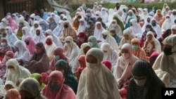 Muslims wear face mask as a precaution against the coronavirus during Eid al-Fitr prayer marking the end of the holy fasting month of Ramadan on a street in in Bekasi, West Java, Indonesia, Thursday, May 13, 2021. Muslims celebrated Eid al-Fitr in a…