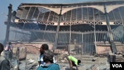 People stand in front of fire-damaged Iron Market in Port-au-Prince, Haiti, Feb. 13, 2018. (F. Lisené/VOA Creole)