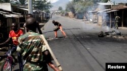 Un homme dégage une barricade alors que les soldats patrouillent dans une rue de Bujumbura, Burundi 15 mai 2015. REUTERS/Goran Tomasevic.