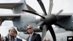 British Prime Minister Theresa May, left, speaks with Airbus CEO Tom Enders, from Germany, in front of an Airbus A400M Atlas military transport aircraft at the Farnborough Airshow in Farnborough, England, Monday, July 16, 2018. (AP Photo/Matt Dunham)