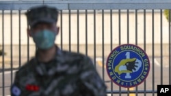 In this Feb. 21, 2020, photo, a South Korean marine wearing a mask stands in front of the Navy Base after a soldier of the unit was confirmed to have been infected with the coronavirus on Jeju Island, South Korea. The U.S. and South Korean…