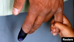 Seorang anak memegang tangan ayahnya yang telah memberikan suara di sebuah TPS di Kabul (14/6).