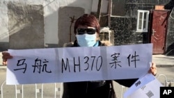 一名马航MH370航班乘客家属手拿标语。（美联社2023年11月27日）