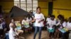 FILE - A charity worker, center, from the GOAL Ireland humanitarian agency, educates children on how to prevent and identify the Ebola virus in their communities at Freetown, Sierra Leone.